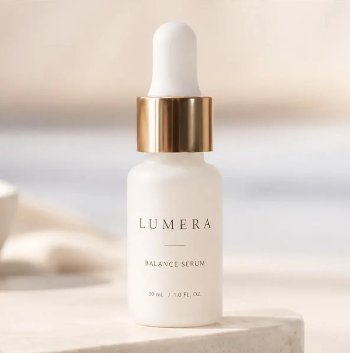 LUMERA BALANCE SERUM の商品画像。淡いベージュの背景に、金色のキャップが付いた白い美容液ボトル